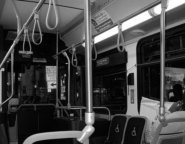 Black-and-white image of an almost empty city bus interior