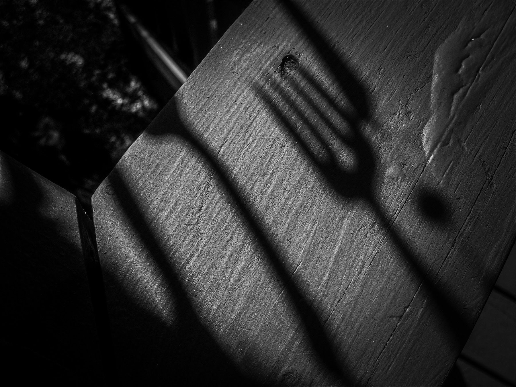 Black-and-white image of stretched shadows of hanging wind chimes made with old silverware