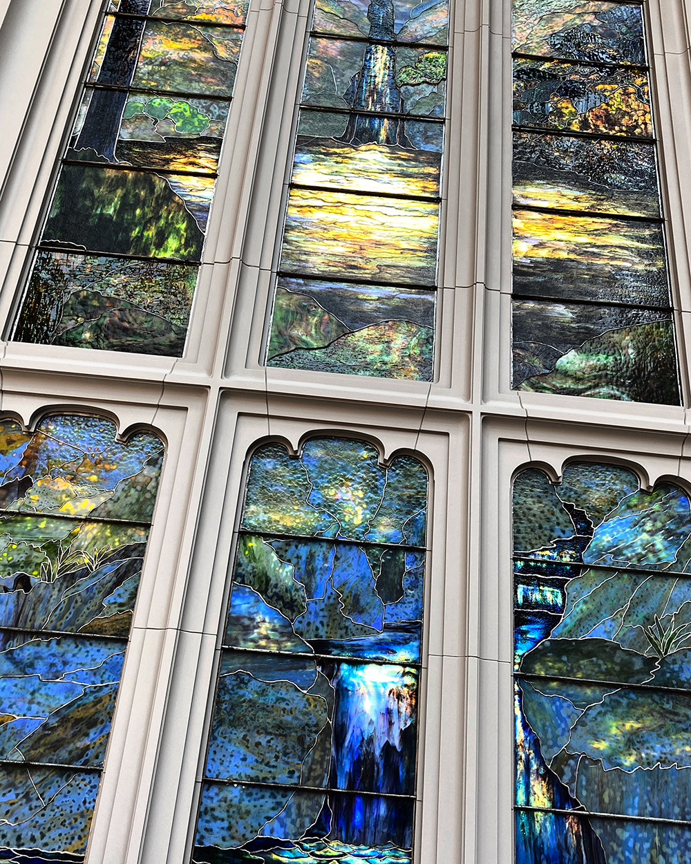 tilted view of a huge stained glass window with blue and green shades