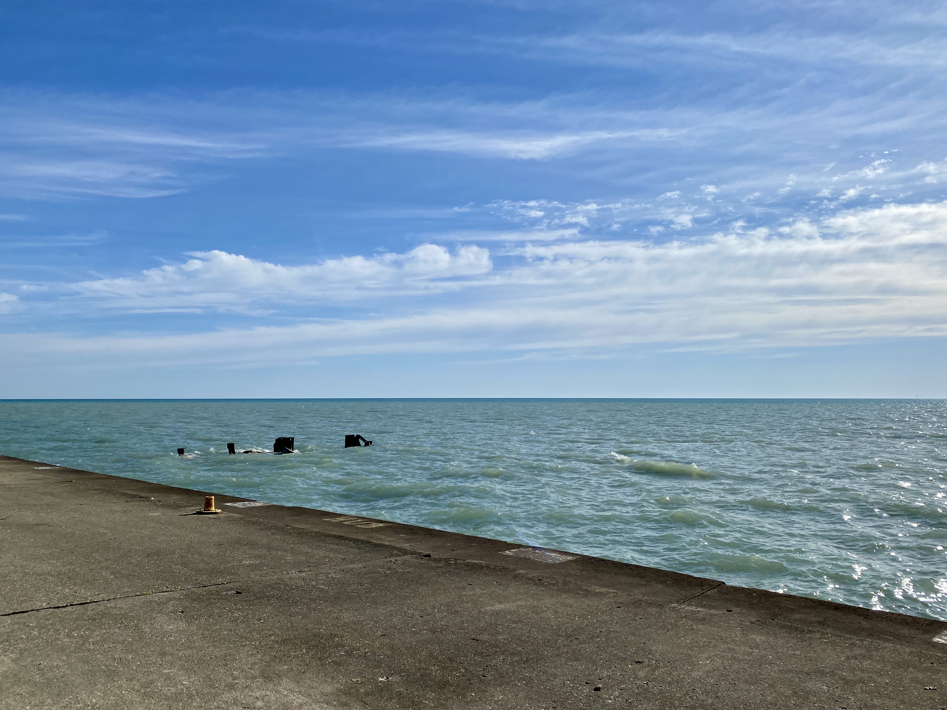 Horizon of large Lake Michigan with a bright blue sky swept with clouds and turquoise-shaded water with small waves