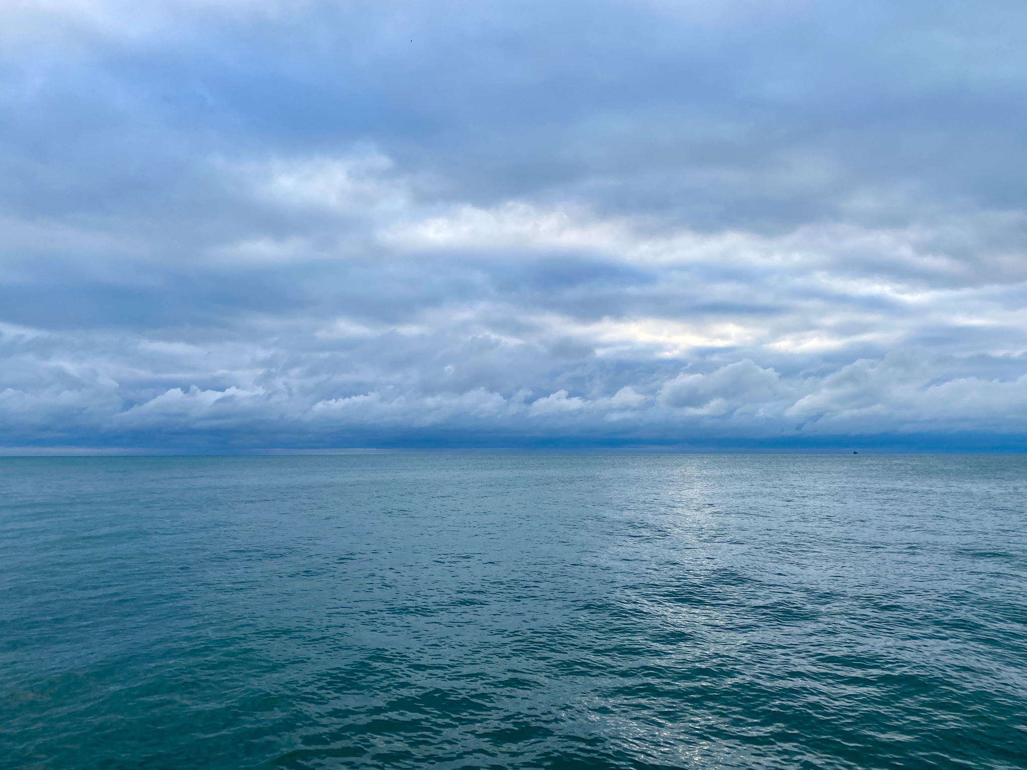A wide lake horizon with a heavily clouded sky in grey and blue