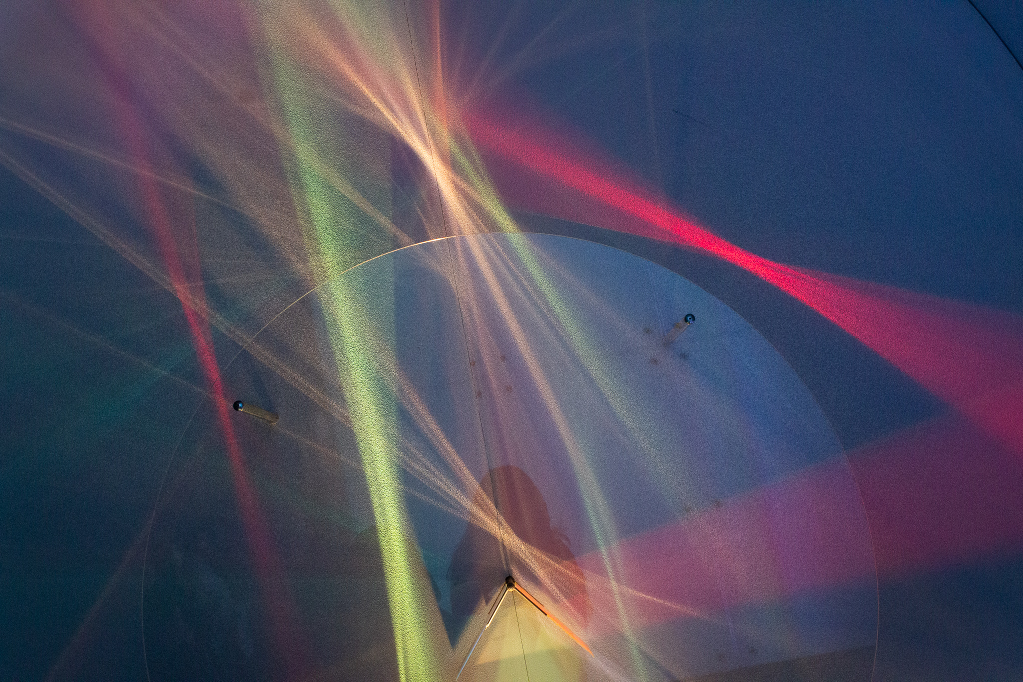 Beams of pastel-colored refracted light with the faint shadow of the photographer in the center