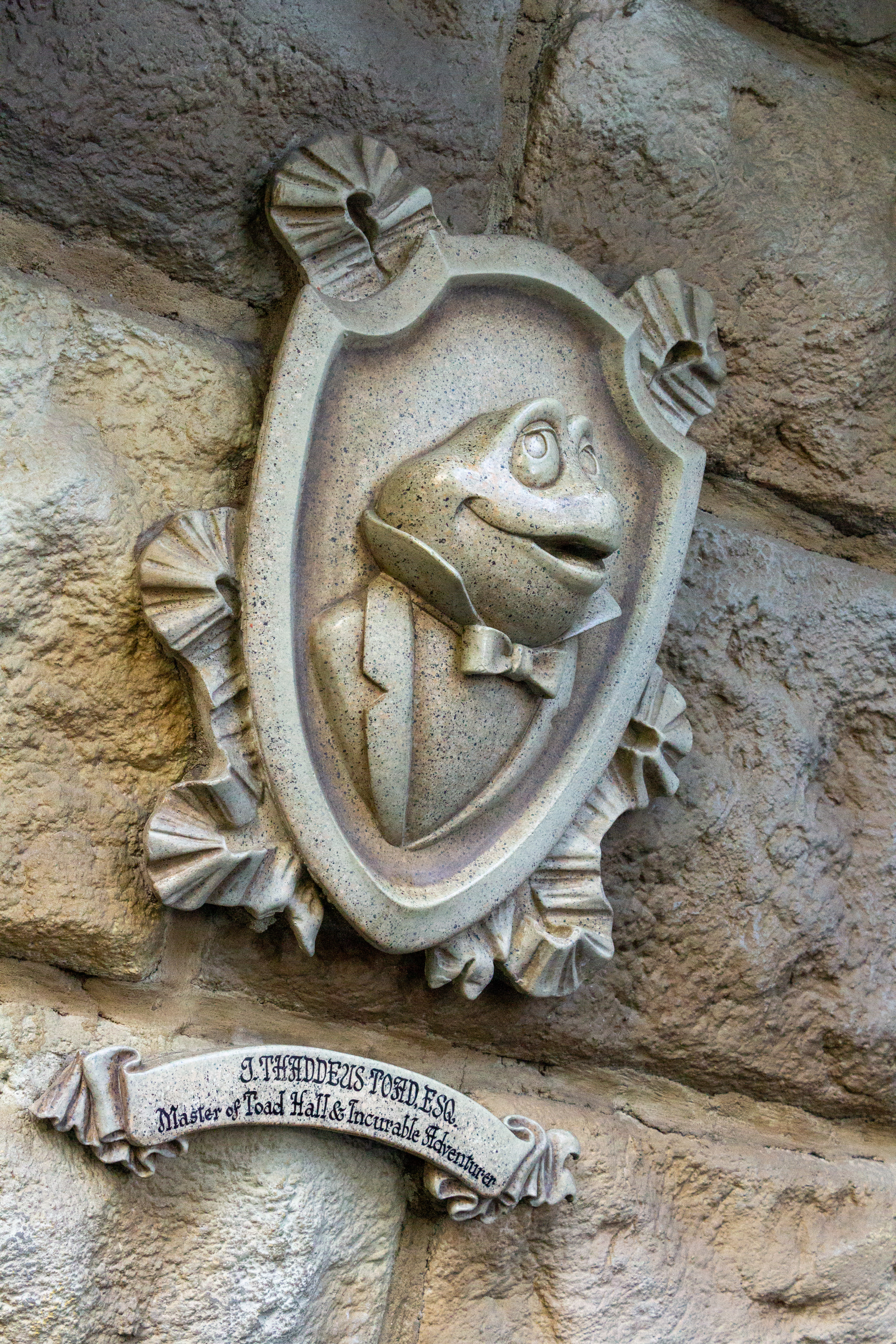 A beige-colored stone relief portrait of Mr. Toad at Mr. Toad's Wild Ride