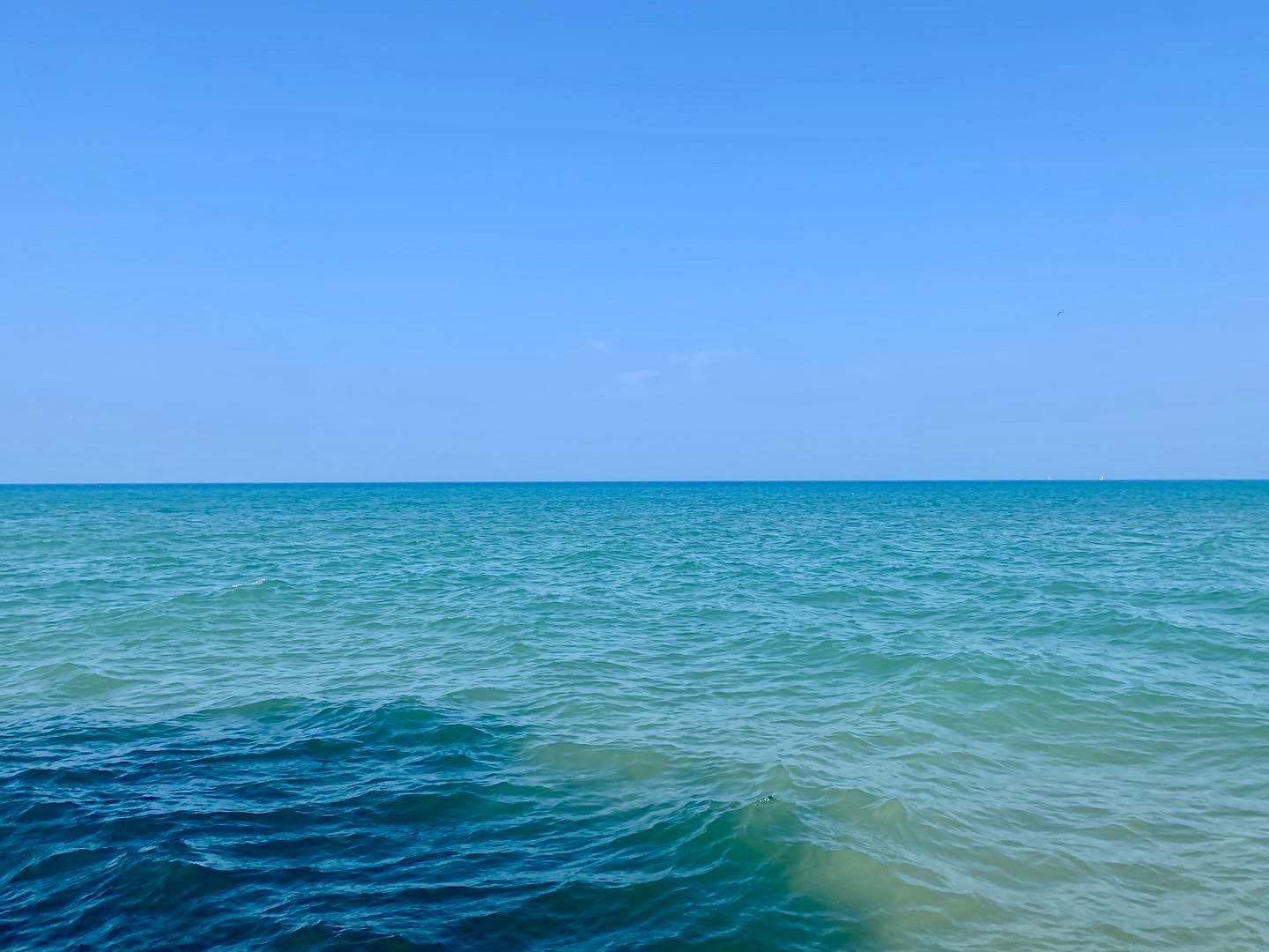 Bright, clear blue sky above a turquoise-colored lake horizon