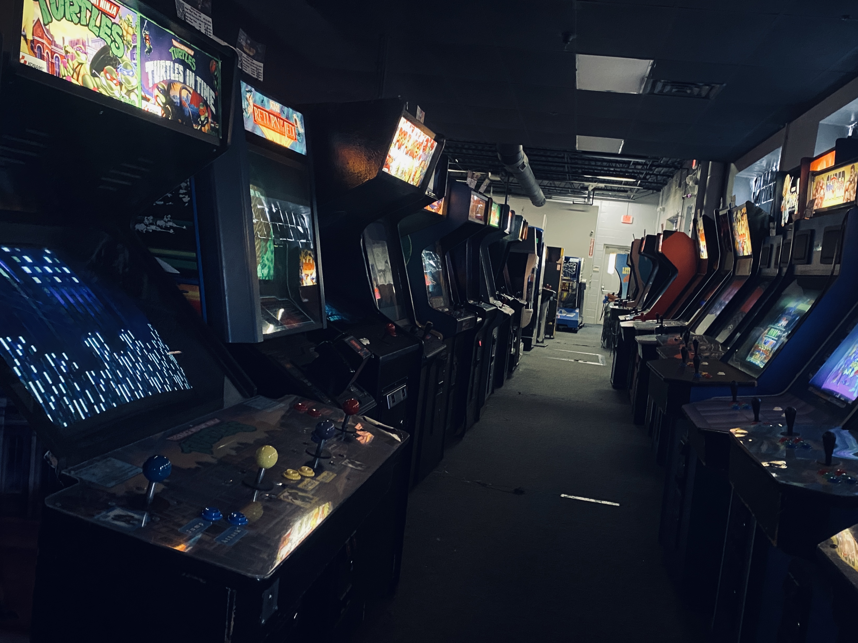 An empty, darkened aisle lined with vintage video game cabinets