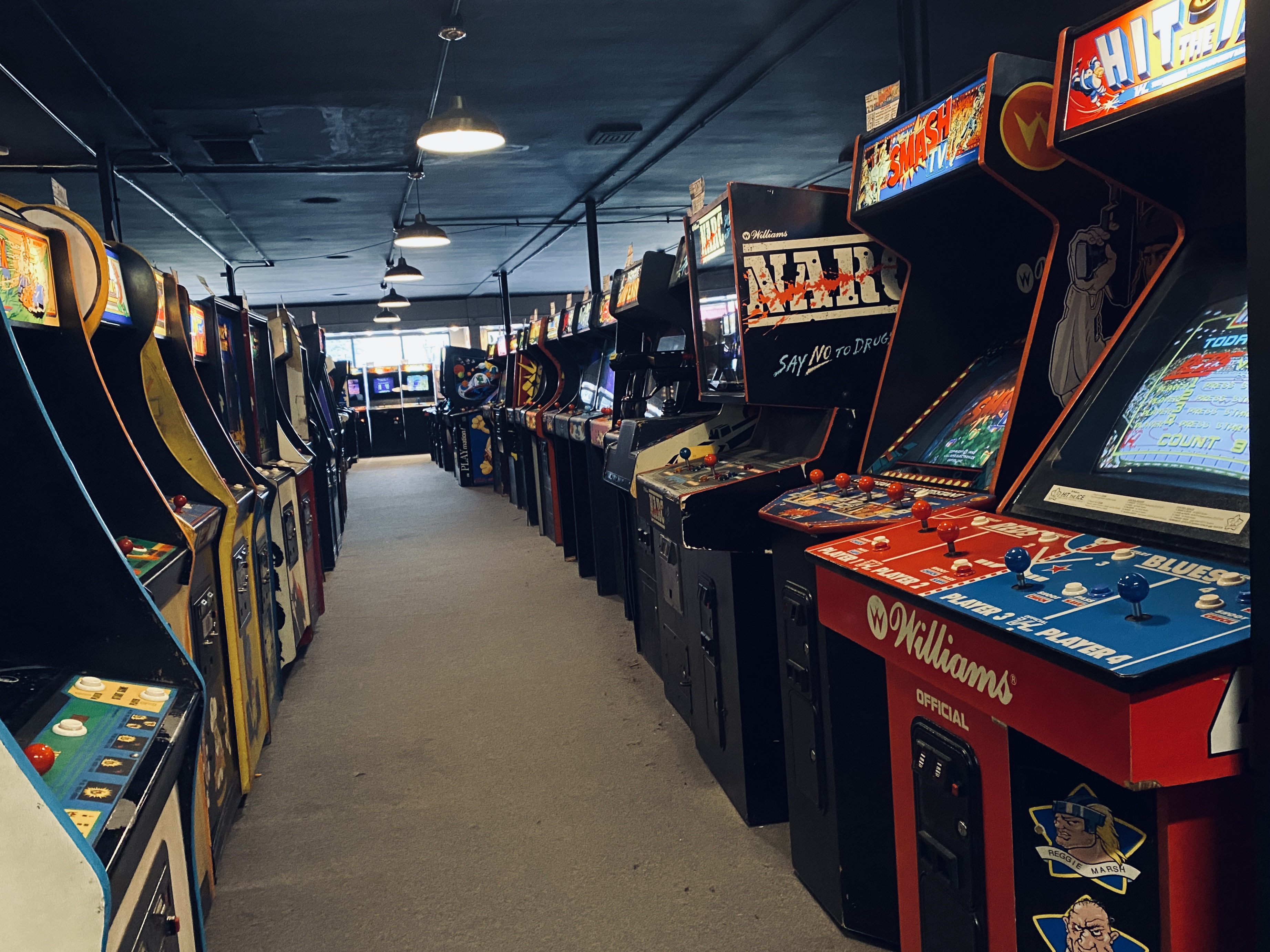 An empty aisle lined with vintage video game cabinets