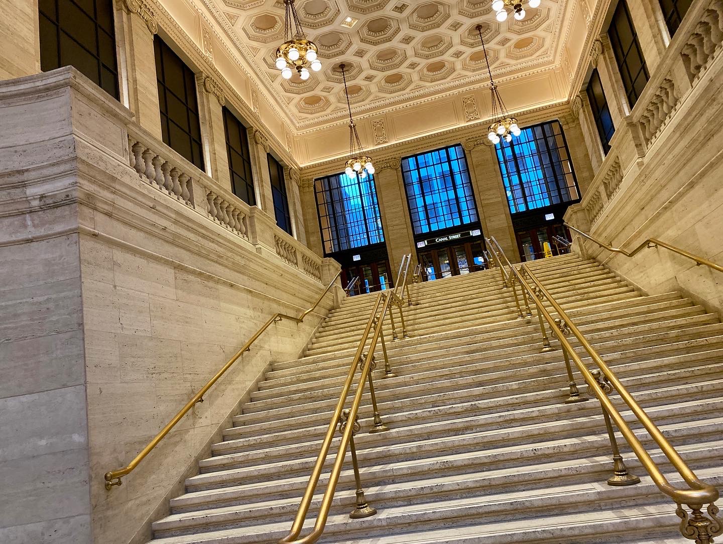 Angled view of stairs in Union Station leading up to the street, lined with brass railings